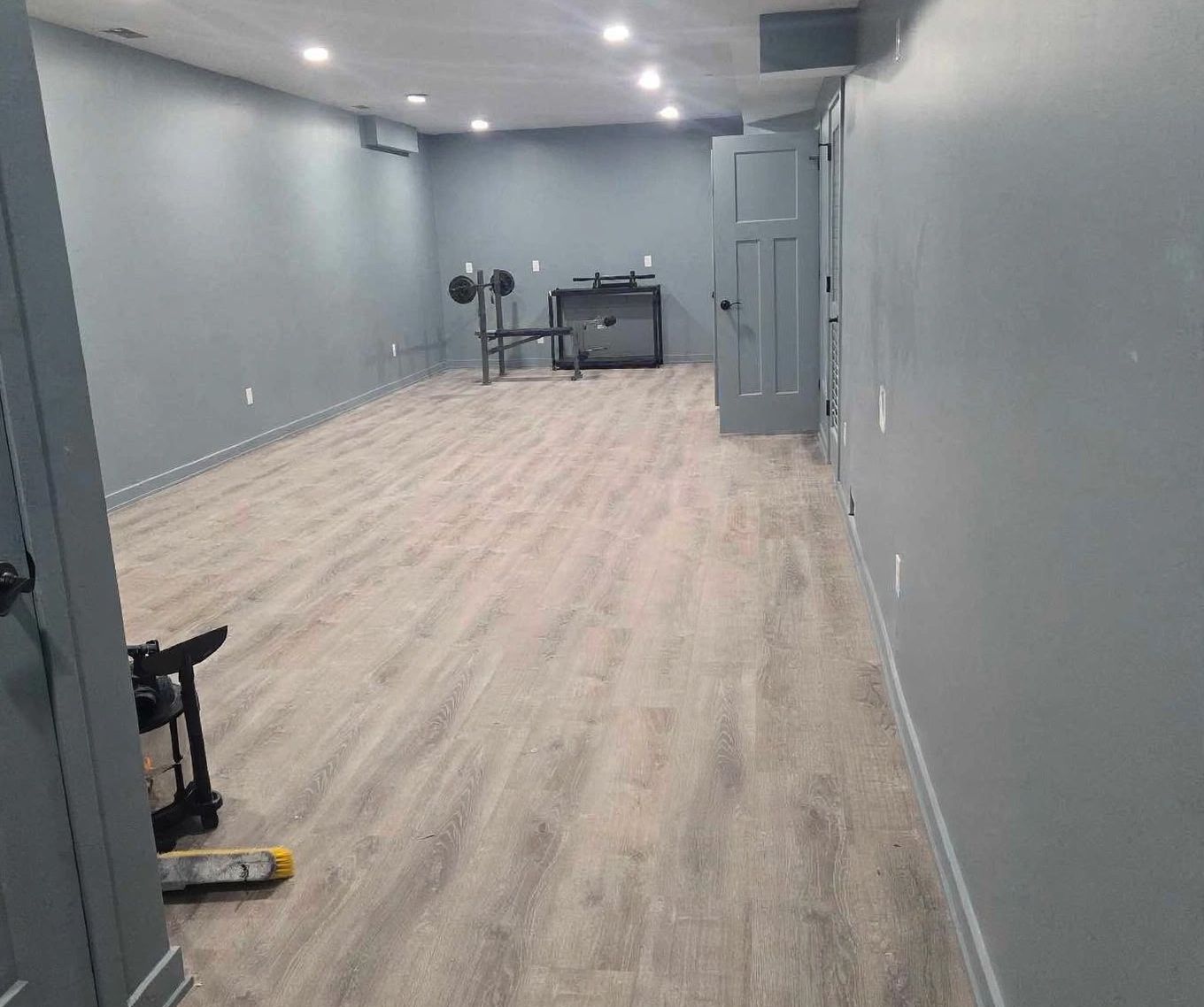 Finished basement with grey walls, recessed lighting and vinyl plank flooring