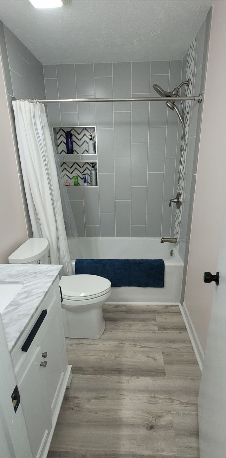 Remodeled bathroom with a floor-to-ceiling tiled tub surround and new vanity