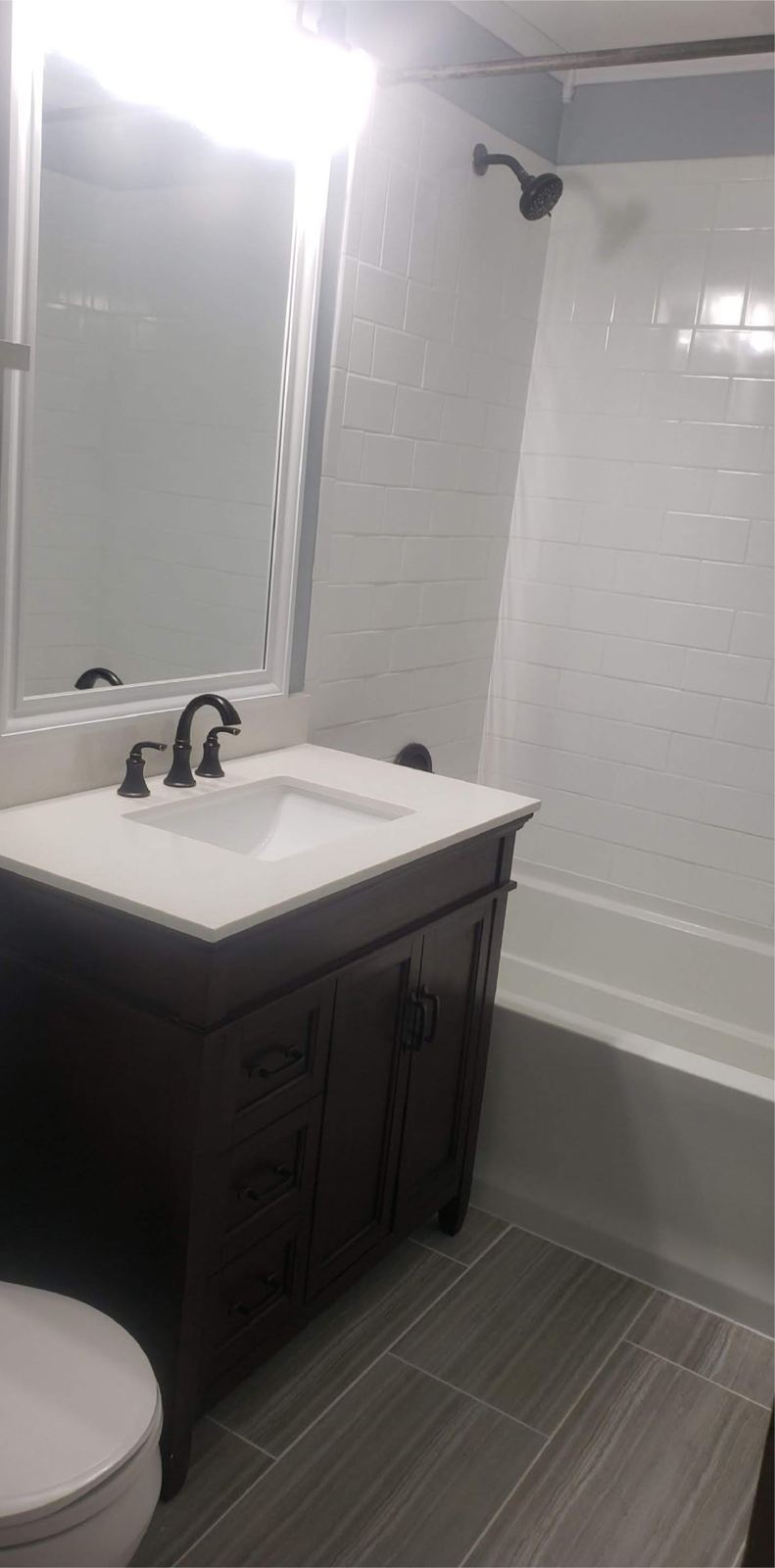 Bright remodeled bathroom with white subway tile and a dark vanity