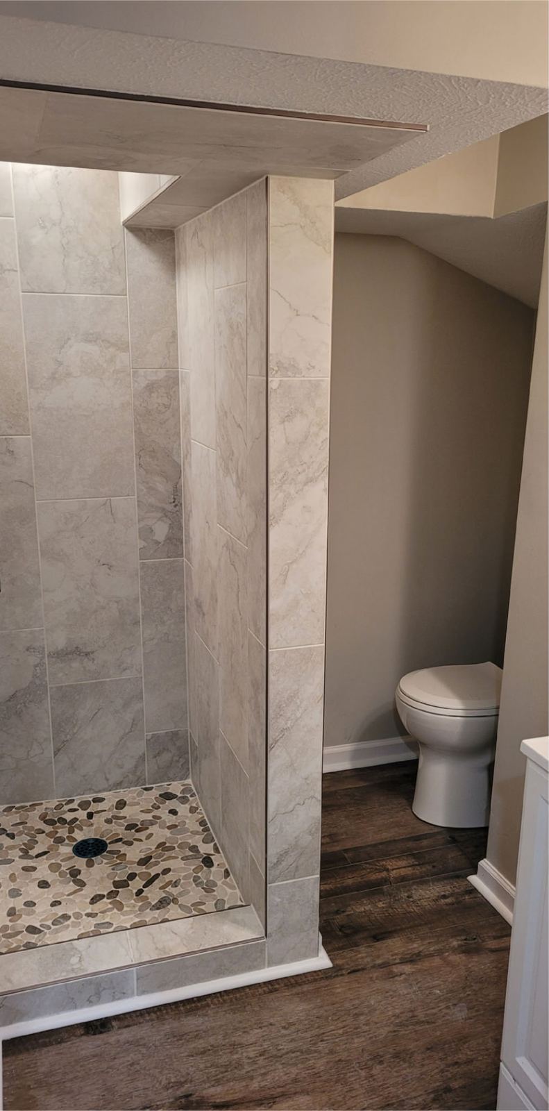 Rebuilt basement bathroom with a full-height tiled shower and pebble floor