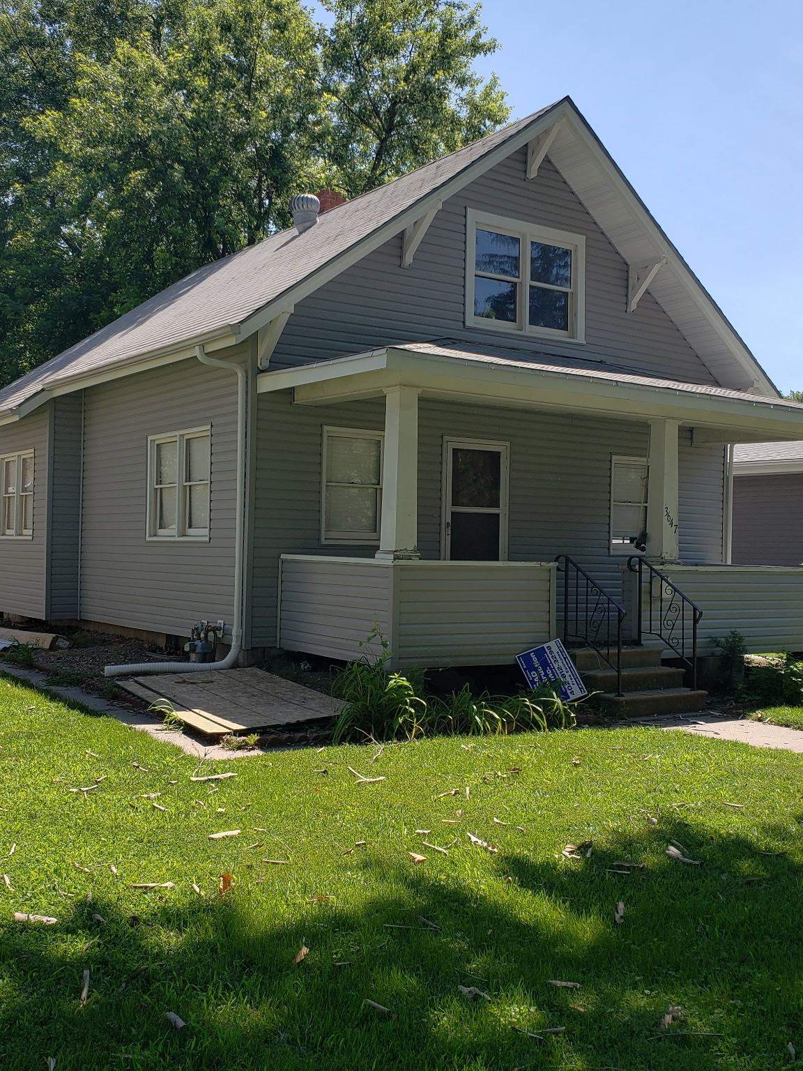 Bungalow finished in grey siding with green trim after exterior renovation