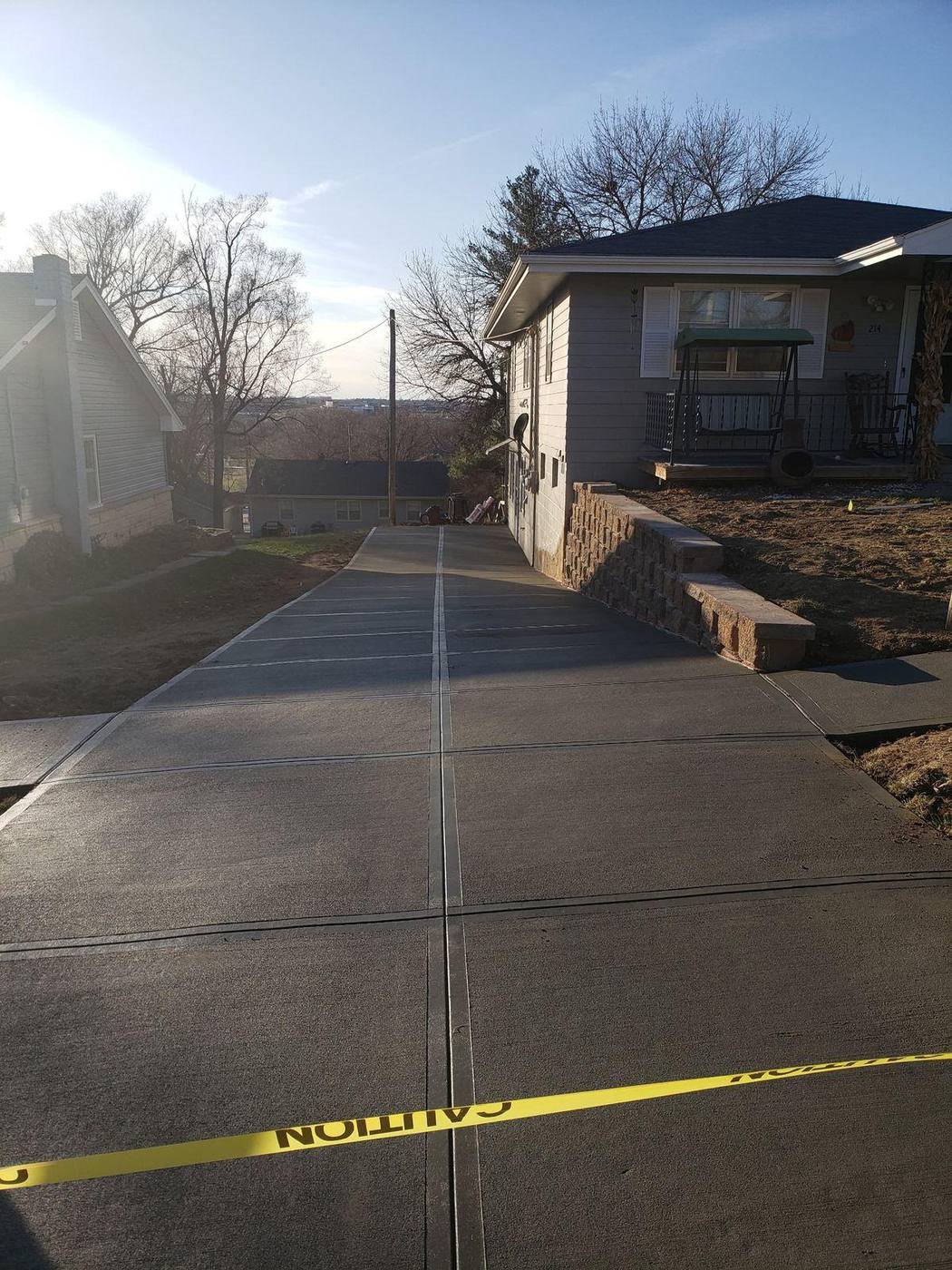 Newly poured concrete driveway running alongside the house with a block retaining wall