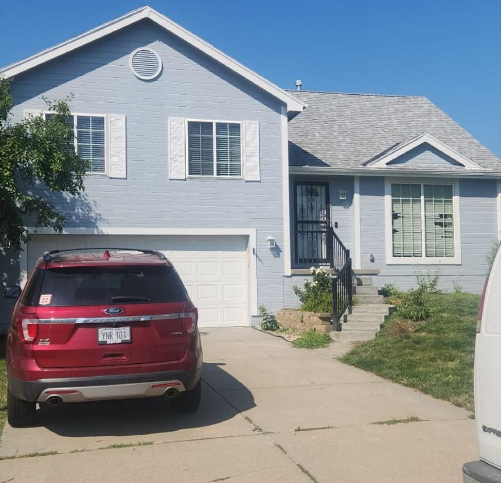 Same split-level house repainted in soft blue-grey with white trim