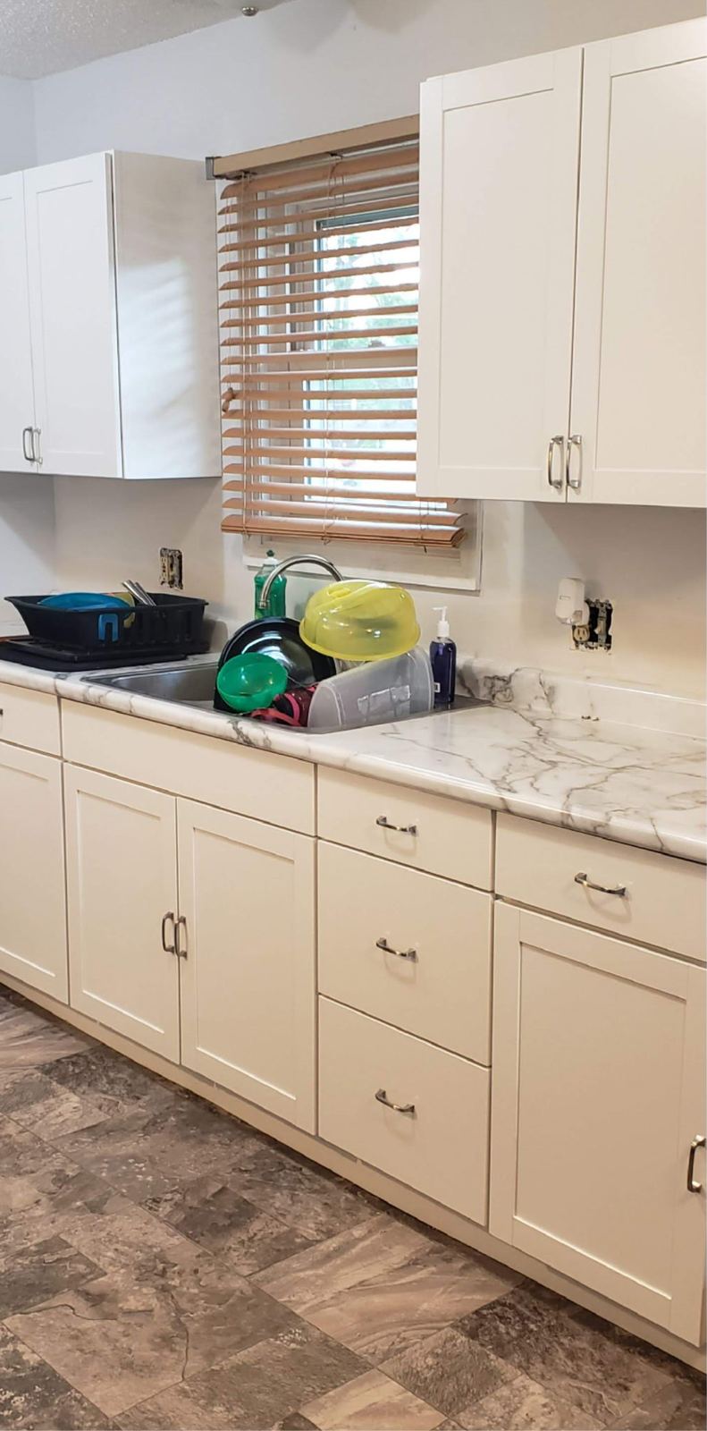 Kitchen with off-white cabinets, marble-look countertops and new plank flooring