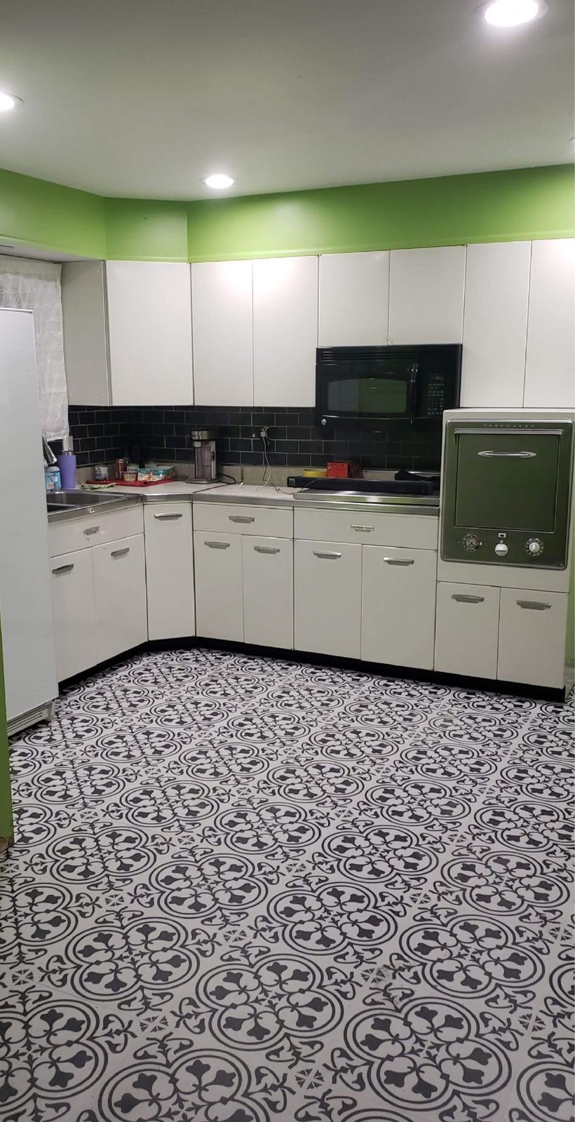 Renovated retro kitchen with black subway backsplash and patterned tile floor
