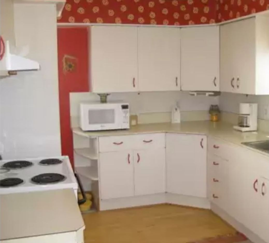 Dated kitchen with red walls, white cabinets and an electric coil range before remodeling