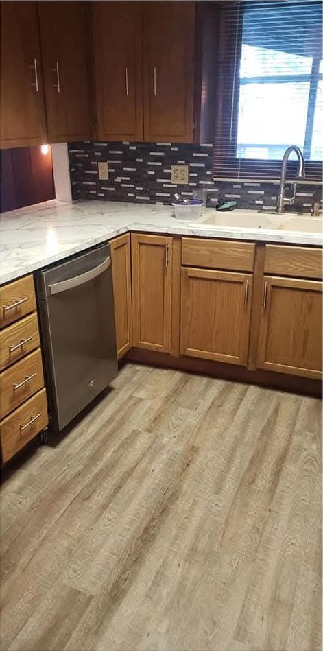 Refreshed kitchen with marble-look counters, glass tile backsplash and plank flooring