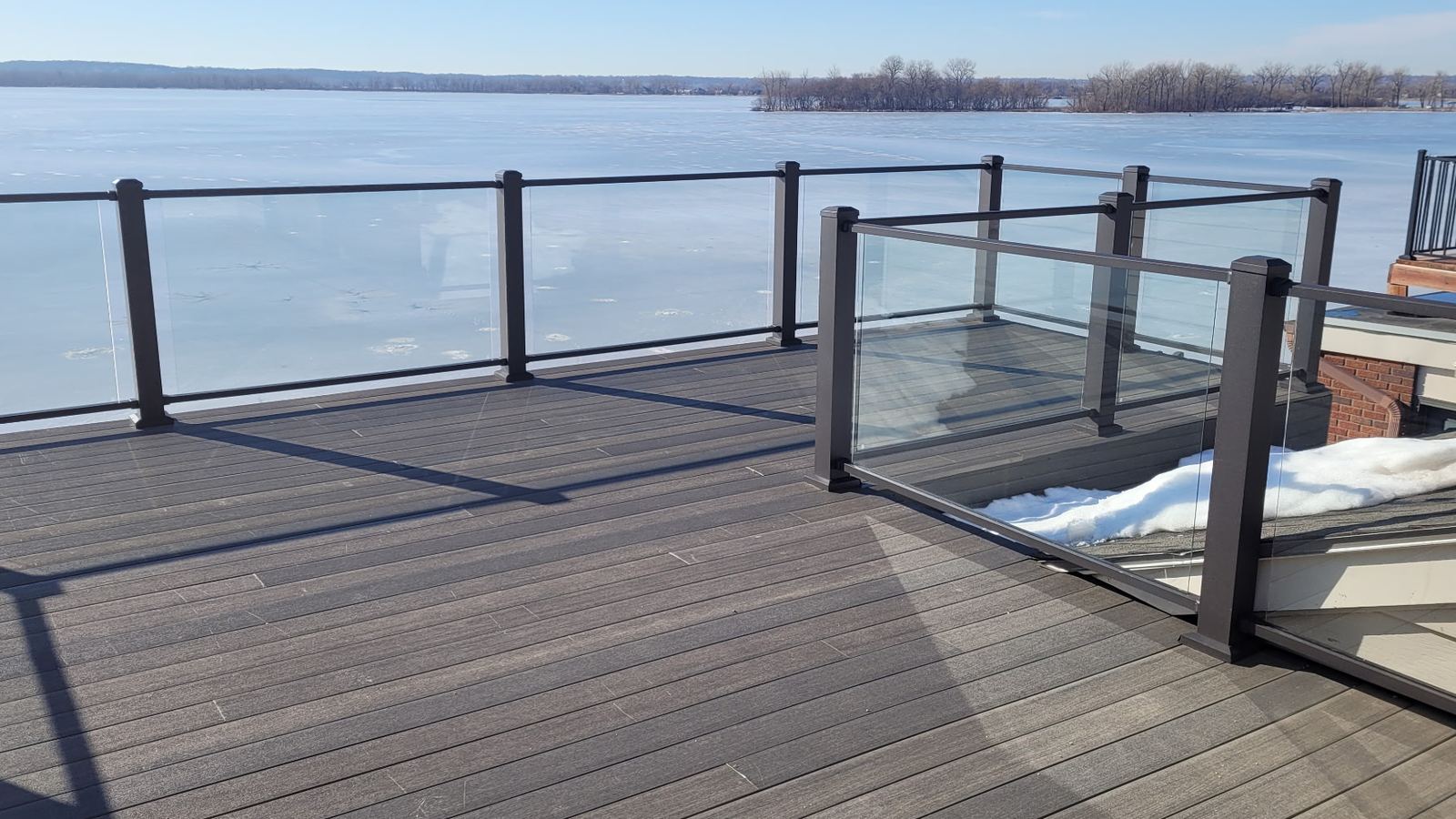 Rebuilt composite deck with a glass panel railing overlooking the lake
