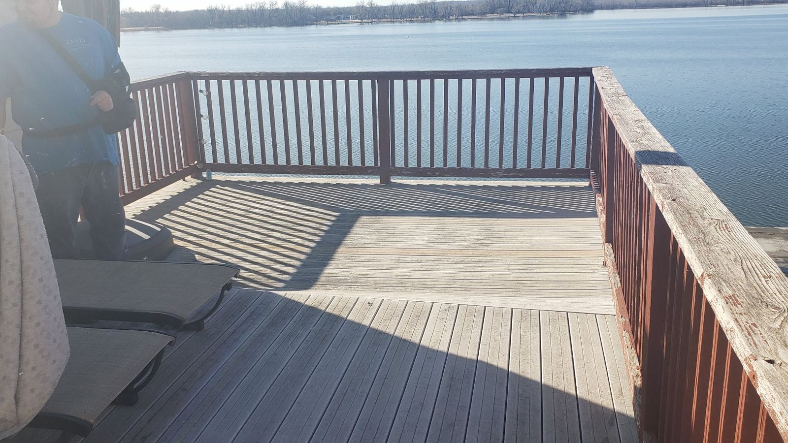 Old wood lakeside deck with a solid railing blocking the water view