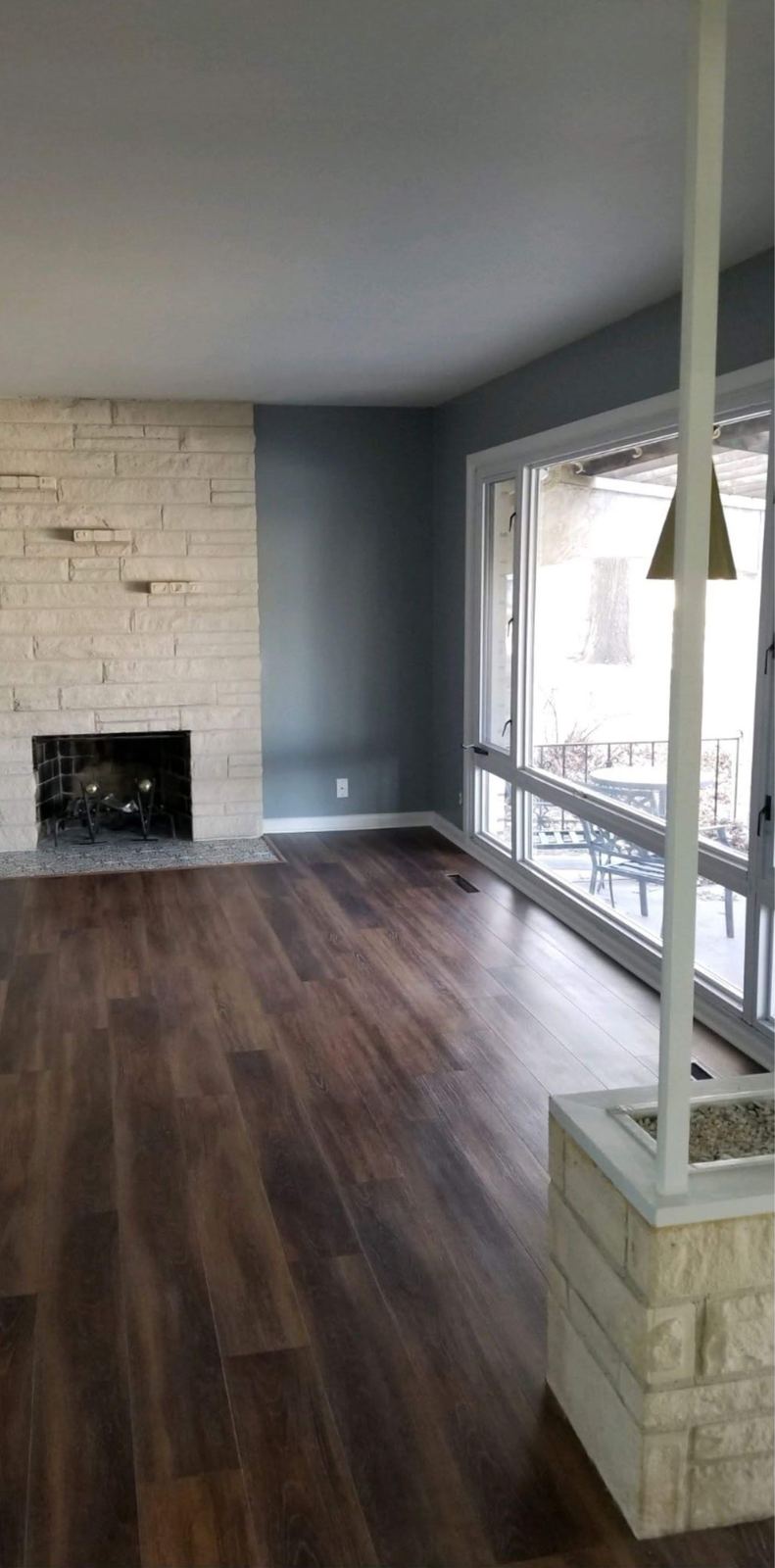 Living room with wide plank flooring and a repainted stone fireplace