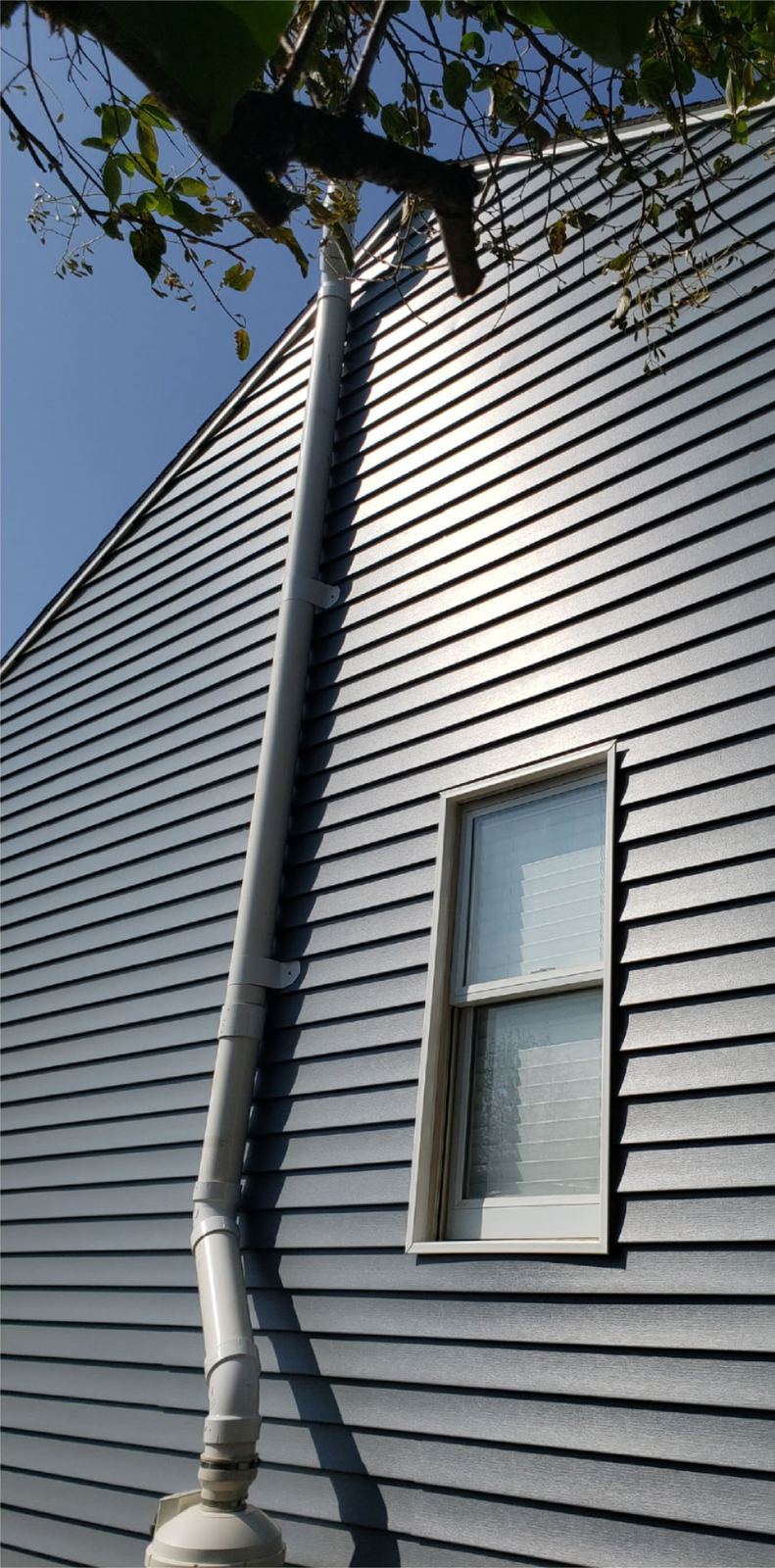 Repaired gable end with new grey lap siding and downspout