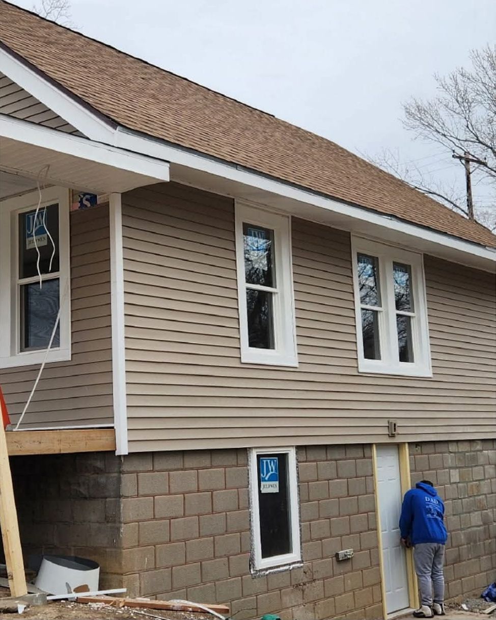 Same house rebuilt with a new porch roof, new windows and tan siding